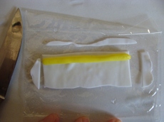На белый пласт укладываем желтую колбаску и обрезаем выступающие края